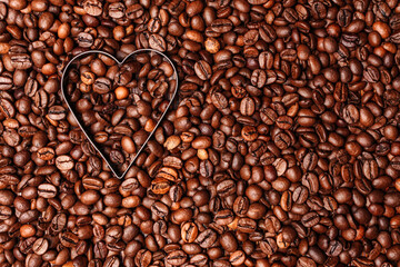 Background from coffee grains and a heart from coffee, the top view