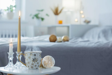 cup of coffee with christmas balls on little table in white bedroom
