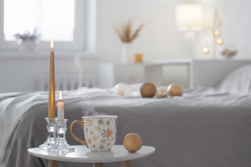 cup of coffee with christmas balls on little table in white bedroom