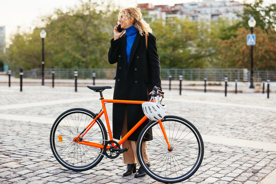 Elegant female cyclist talking on cellphone