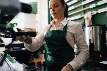 Caucasian female barista at work making coffee