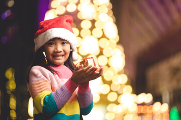 Happy child in Santa red hat holding Christmas presents. Christmas time.