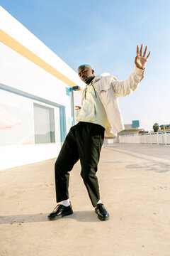 Cool stylish black man doing dance movement on street