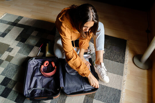 Female packing suitcase on the floor