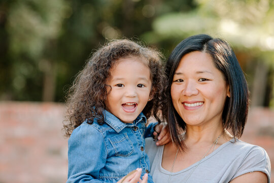 Happy Asian mom holding multiracial girl