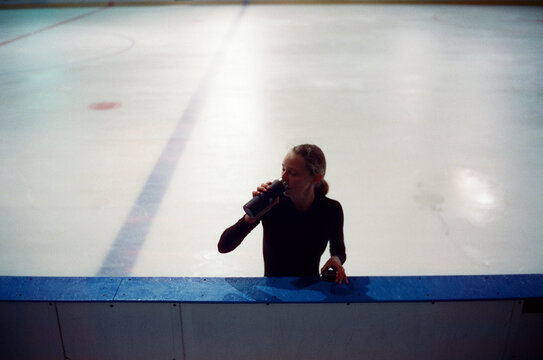 Girl on the ice stopped for a break and a drink a water
