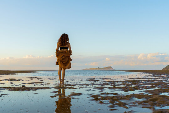 Woman enjoying sunset on empty wild beach