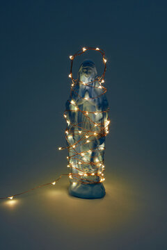 Virgin Mary statue with glowing garland in dark