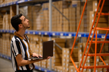 Worker looks up with Laptop at Warehouse