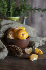 Juicy fresh tangerines lie in a brown ceramic bowl.