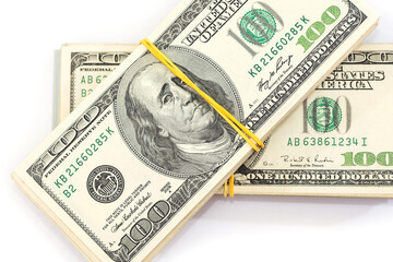 two bundles of one hundred dollar bills tied with an elastic band, isolated on a white background.