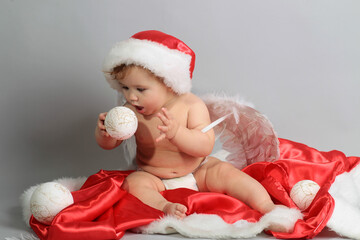 Baby angel first christmas. Beautiful little baby celebrates Christmas. New Year's holidays. Baby with santa hat with gift. Santa baby.