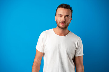 Portrait of smiling handsome guy in white t-shirt over blue background