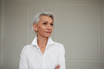 Portrait of an adult elderly self-confident woman with white hair looking awey into distance in...