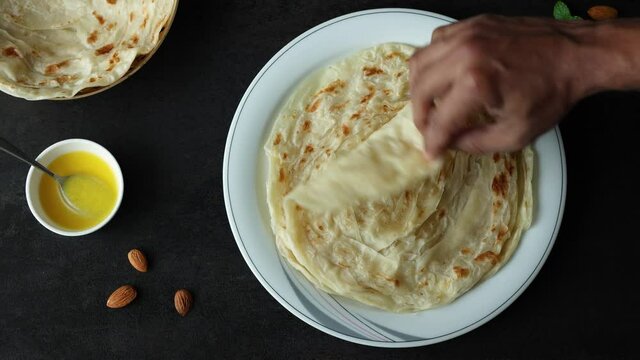 Indian flat bread Kerala porotta woman hand serving eating Malabar porotta paratha layered bread 4K video footage whole wheat flour Maida India  chapati fulka parantha rumali roti side dish meat curry