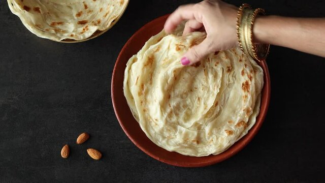 Indian flat bread Kerala porotta woman hand serving eating Malabar porotta paratha layered bread 4K video footage whole wheat flour Maida India  chapati fulka parantha rumali roti side dish meat curry
