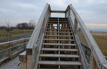 The tourist lookout tower slides dangerously down the wooden stairs in winter. hiker in jeans fell from the skin and injured lying on the steps. legs broken with bruises danger of falling