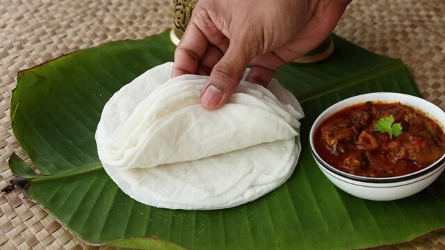 Rice Pathiri pathir flat bread spicy chicken curry woman hand serving traditional South Indian breakfast dish Rice roti 4K video footage Malabar Ramadan Ramzan, Eid festival Kerala India SriLanka
