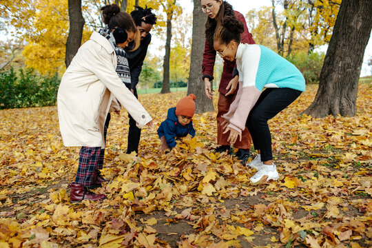 Multiracial family going to tossing autumn leaves