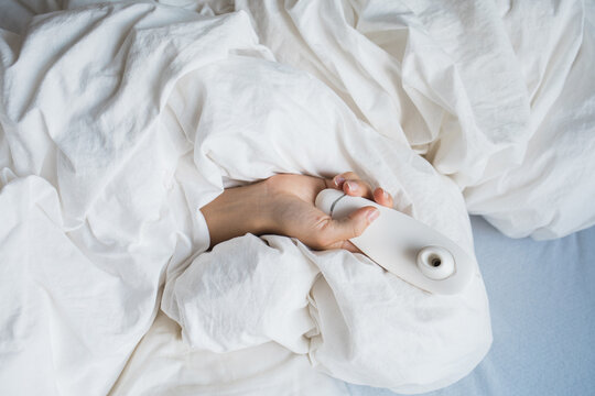 Hand sticking out the sheets with sucking vibrator
