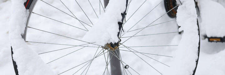 Fototapeta premium Bicycle wheel is covered with snow on street closeup
