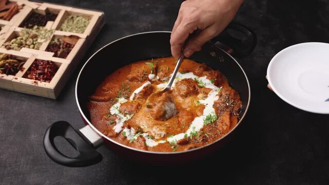 Butter chicken woman hand serving cooking Murgh Makhani curry roast Vindaloo hot spicy dish 4K video footage Dhaba Punjab India North Indian non vegetarian cuisine tikka Masala Chicken curry 