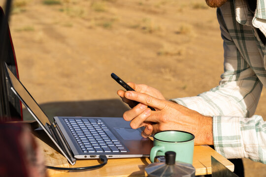 Man working on laptop in the back of a van in desert