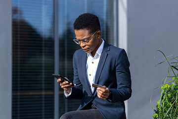 Annoyed and tired African-American woman tries to make an online purchase, uses a phone application...