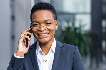 Photo of close up portrait of young handsome business woman, african american woman talking on the phone, smiling and rejoicing happy looking at camera