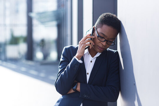 Woman businessman sad complains on the phone, reports bad news, African American woman in despair near the office, holding hands behind his head