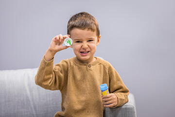 Happy little kid blowing soap bubble at home. Child indoor activity concept. Little caucasian boy...