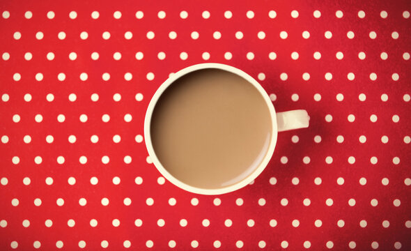 Cup with coffee with milk on Polka dot background.