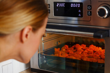 Woman looking at oven with pumpkin