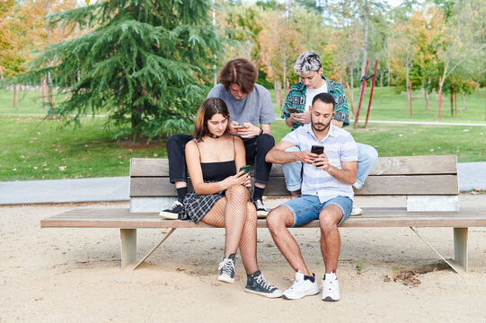 Lgbt friends checking their phones in a park