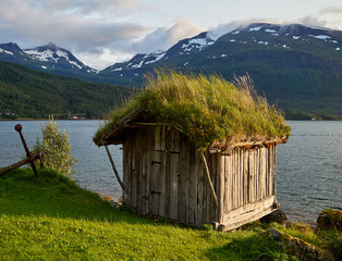 Quaint fjord boathouse with green grass roof, Norway 