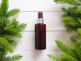 Unbranded brown cosmetic spray bottle and Christmas fir tree on white wooden table. Skincare beauty and liquid antibacterial spray concept. Natural organic spa Body mist. Mockup, closeup, front view.