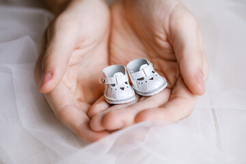 White miniature shoes for a doll made of genuine leather stand on the fingers. Beautiful shoes with...