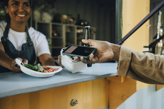 Cropped image of customer doing contactless payment at food truck