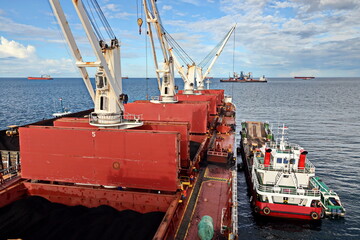 Various bulk carriers, vessels, and tugboats in port under cargo operations and underway. Port of Muara Pantai, Indonesia, January,2021