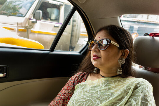Woman wearing Sari and sunglasses travelling in a car 