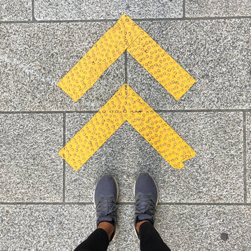 Feet standing by arrows on a sidewalk