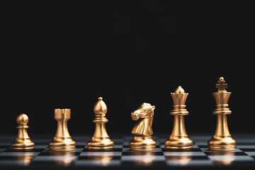 Golden chess include king queen horse ship and pawn on dark background.