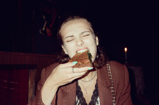 Hungry girl eating a spinach pie at night