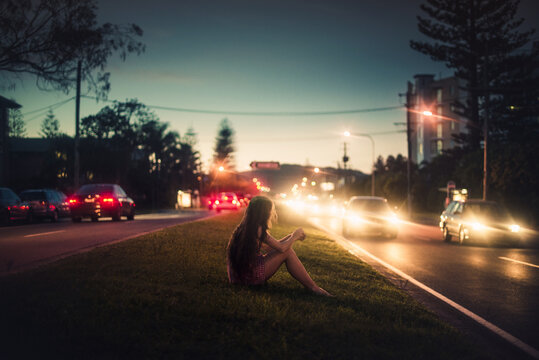 Woman sitting between busy roads