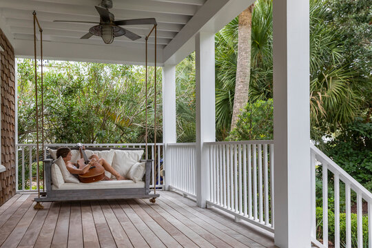 Barefoot Girl Strumming guitar on Porch of home 