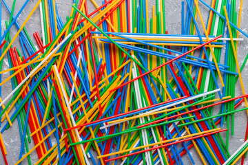 many multi-colored plastic tubes for cocktail on Colored background, top view