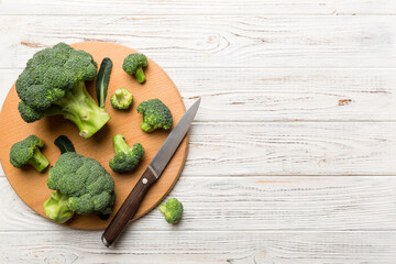 fresh green broccoli on wooden cutting board with knife. Broccoli cabbage leaves. light background. Flat lay