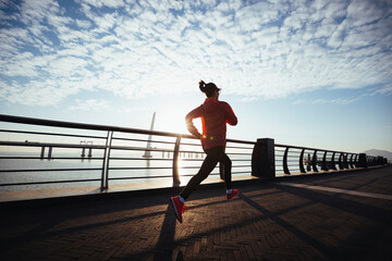 Fototapeta premium Fitness woman runner running on seaside bridge