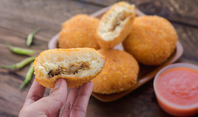hand holding fried bread filled with tuna fish