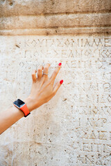 Woman philologist and tourist reads and tries to translate ancient Greek from columns in the ruins...